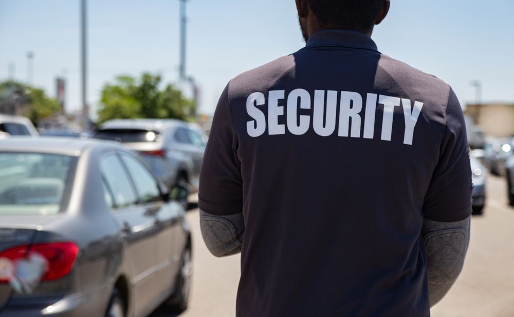 Front Back A Man Wearing A Security Shirt Stands — Professional Security Guards in Longreach, QLD