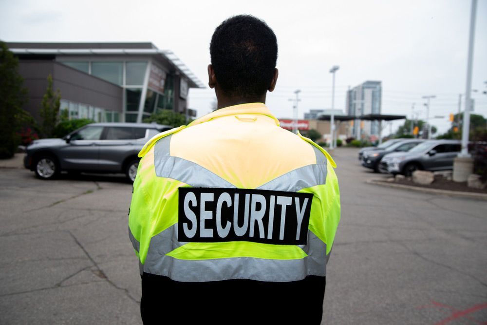 A Man Wearing A Security Vest Stands — Professional Security Guards in Longreach, QLD