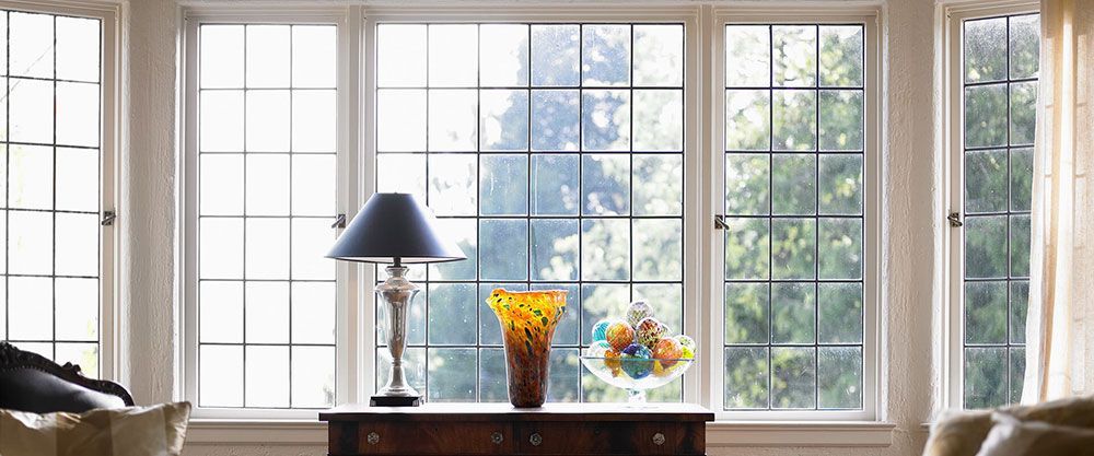 A living room with a large window and a table with a vase of flowers on it.