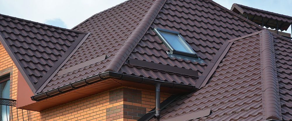 A brick house with a brown roof and a skylight on the roof.