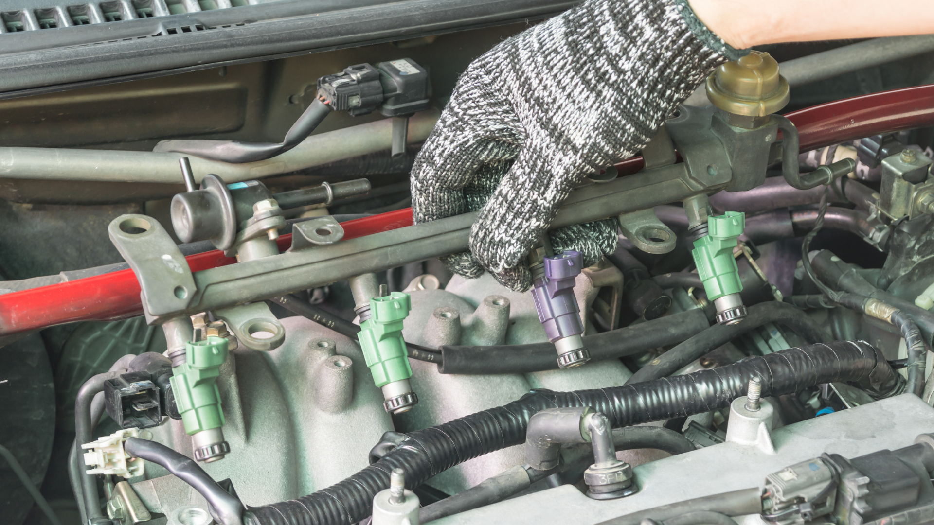 A person wearing a glove is working on a car engine.
