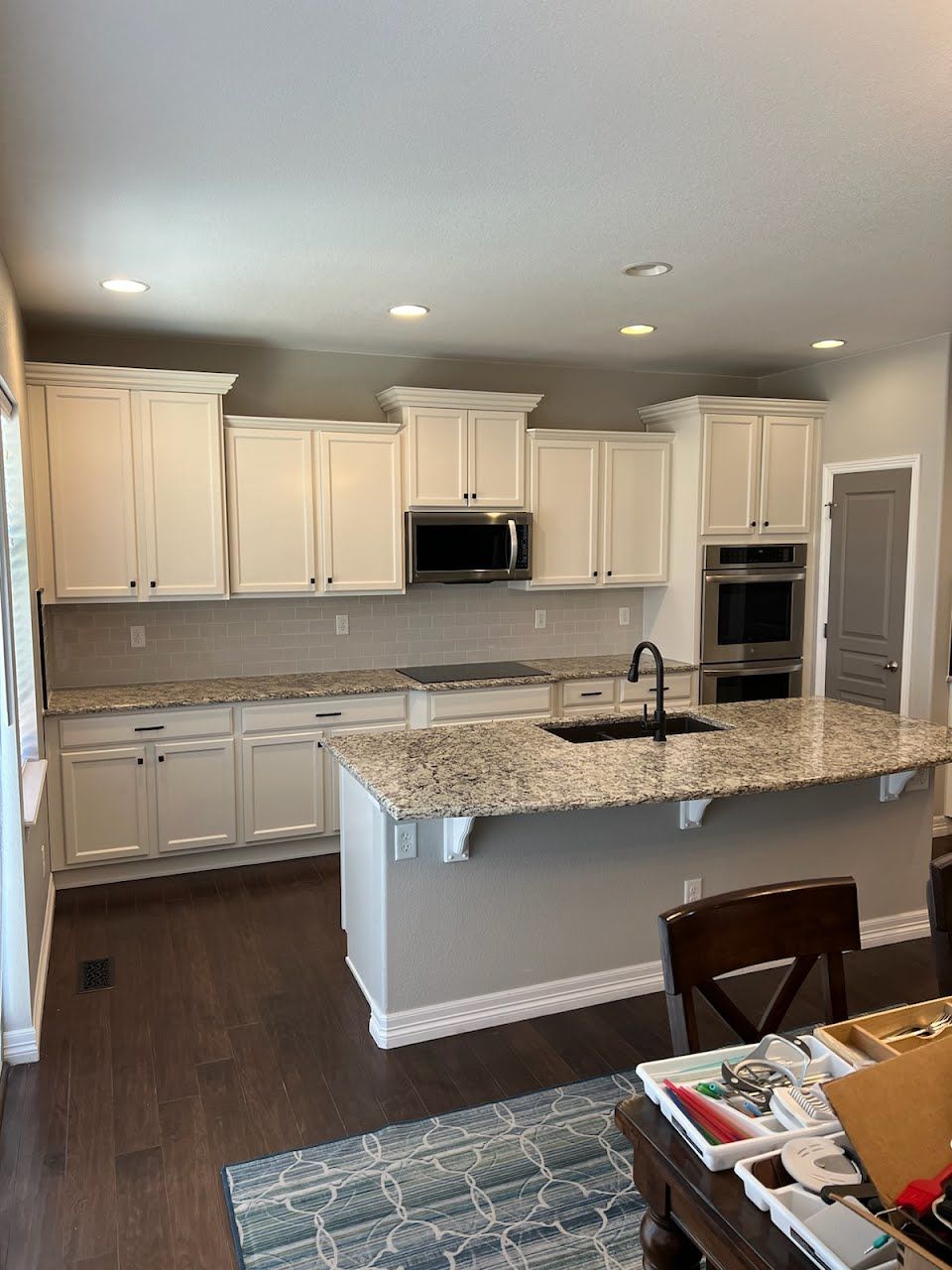 Cream-colored kitchen with granite countertops, stainless steel appliances, and a large island. Dark wood flooring.