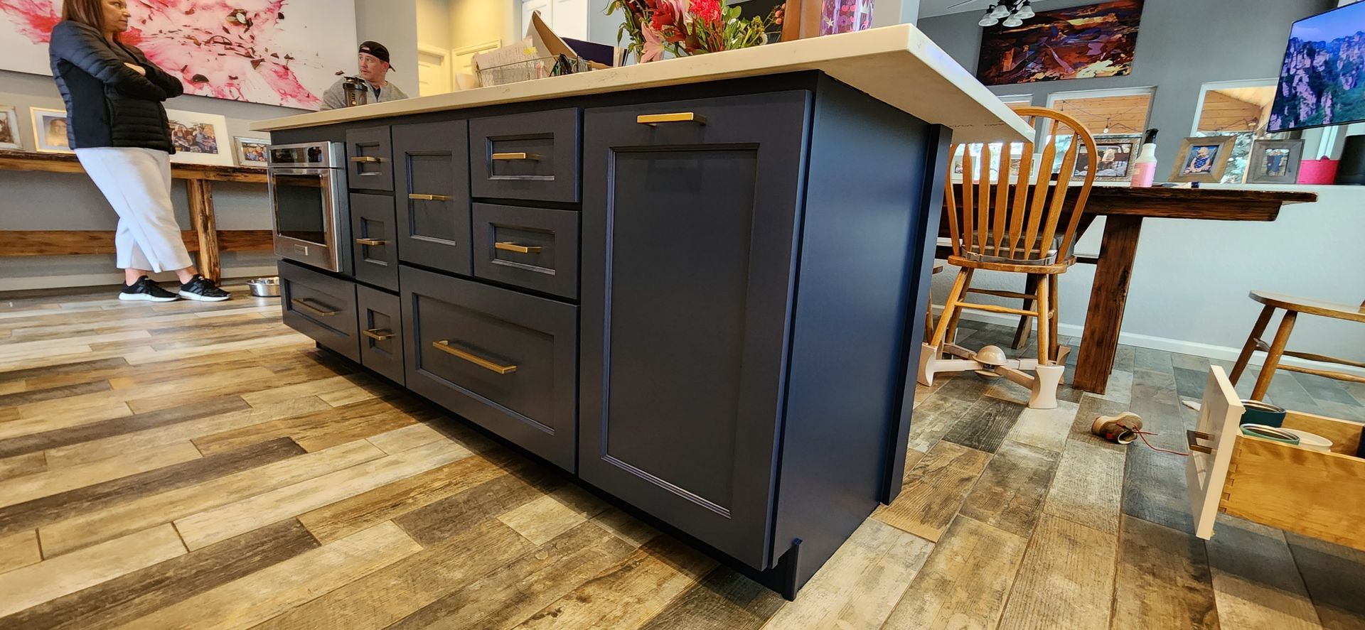 Dark blue kitchen island with drawers and a cabinet, light countertop, wood floor.