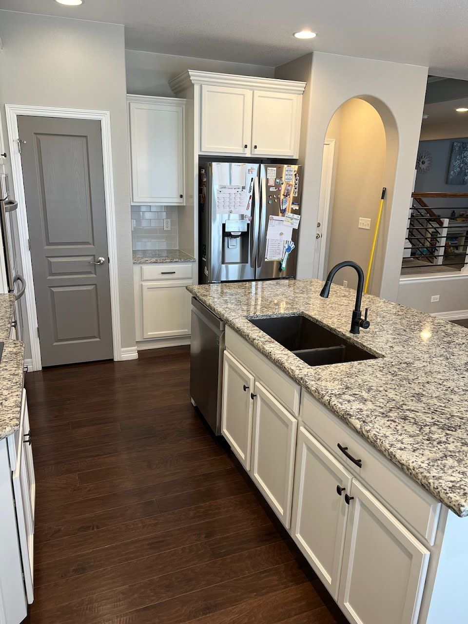 Kitchen with white cabinets, granite countertops, stainless steel appliances, dark wood floor.