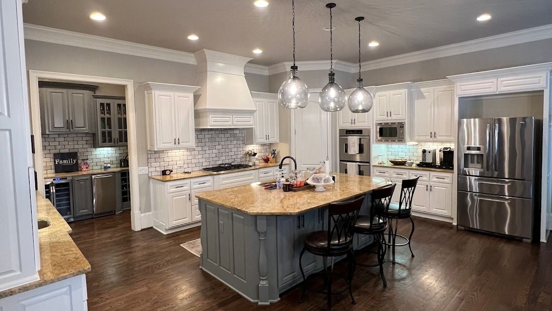 Spacious kitchen with a gray island, light cabinets, and stainless steel appliances.