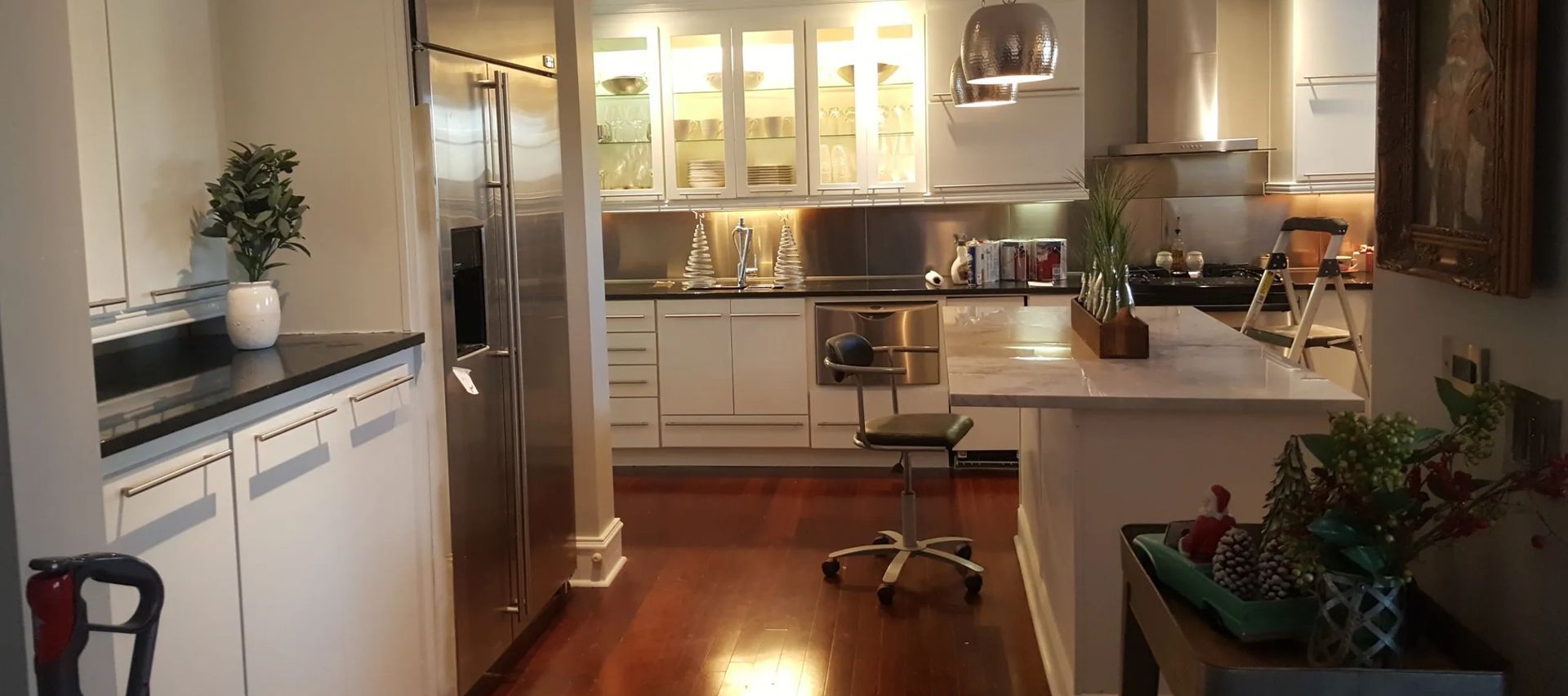 A modern kitchen with white cabinets, stainless steel appliances, and a central island with a stool.