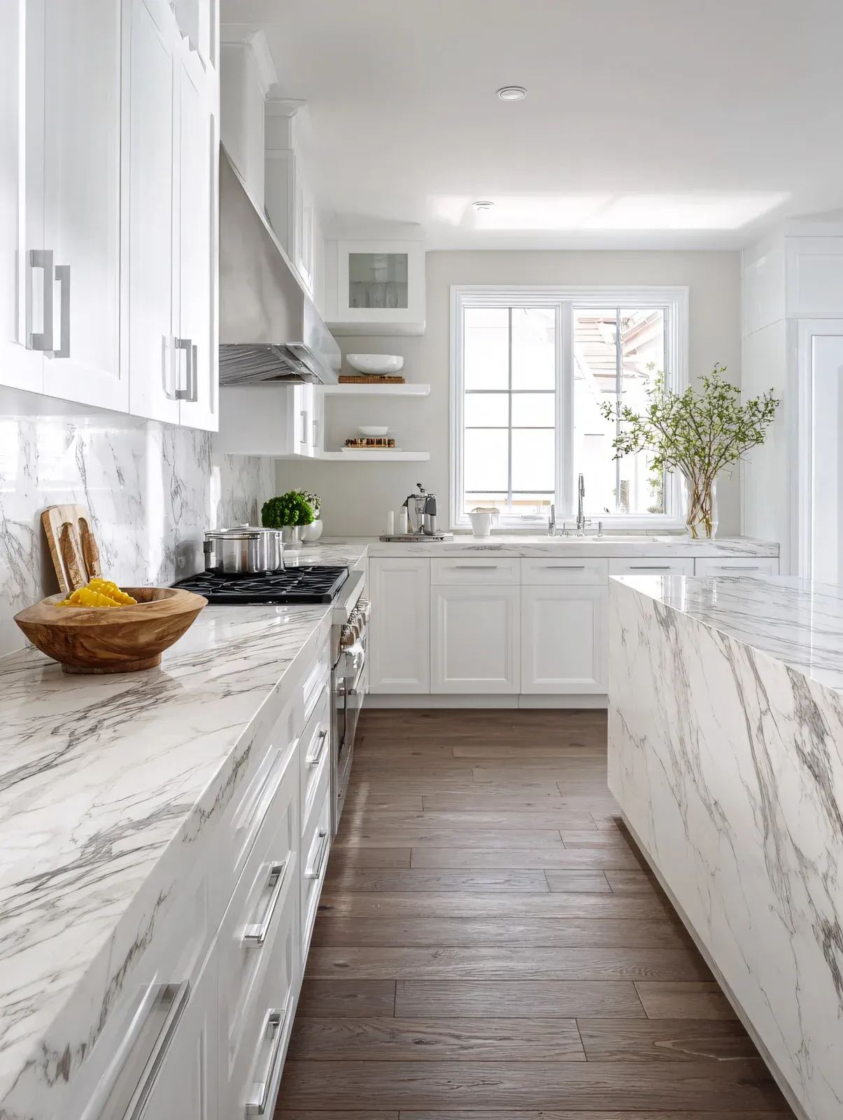 White kitchen with marble countertops, wood floor, and white cabinets.
