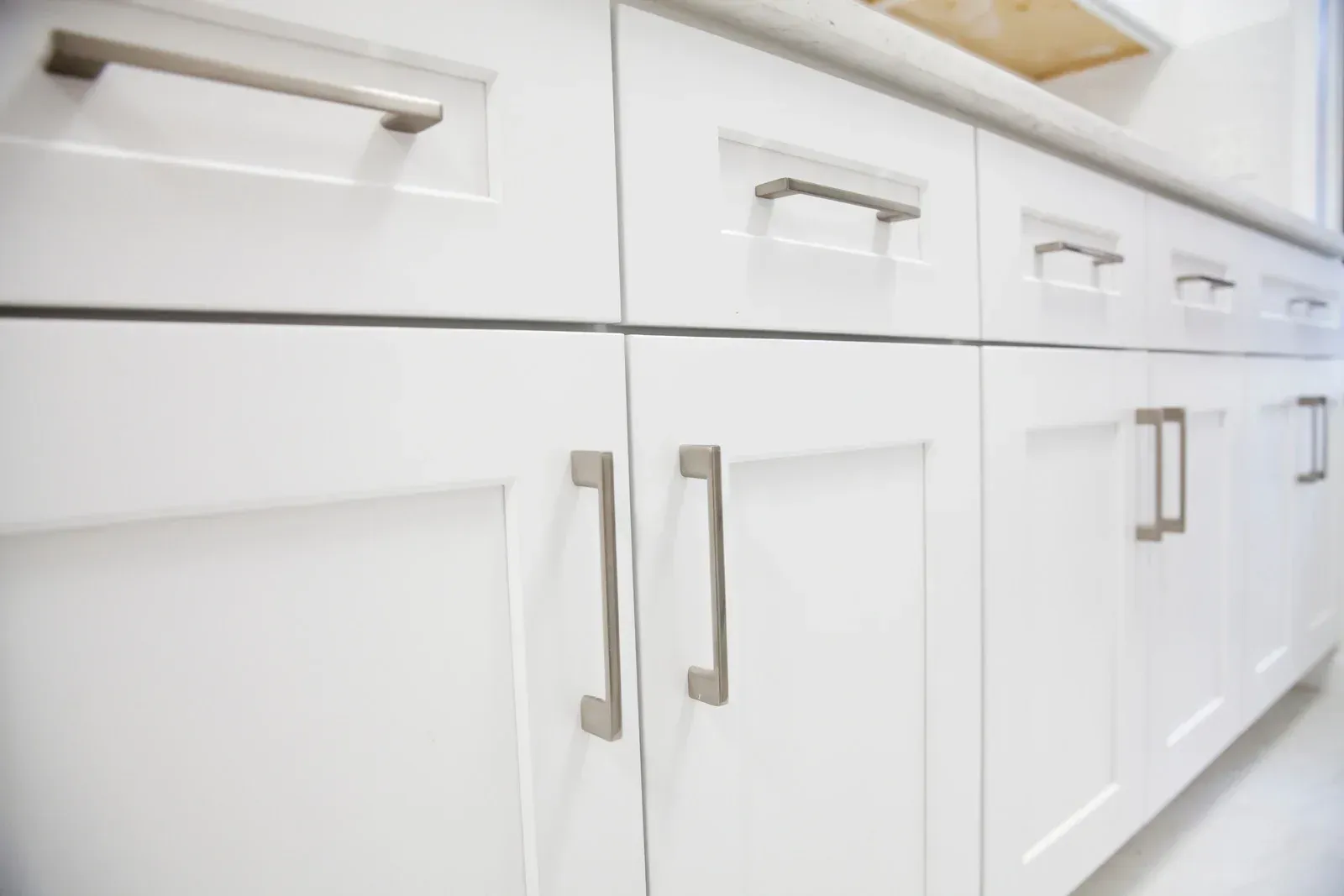 White cabinets with silver handles along a countertop.