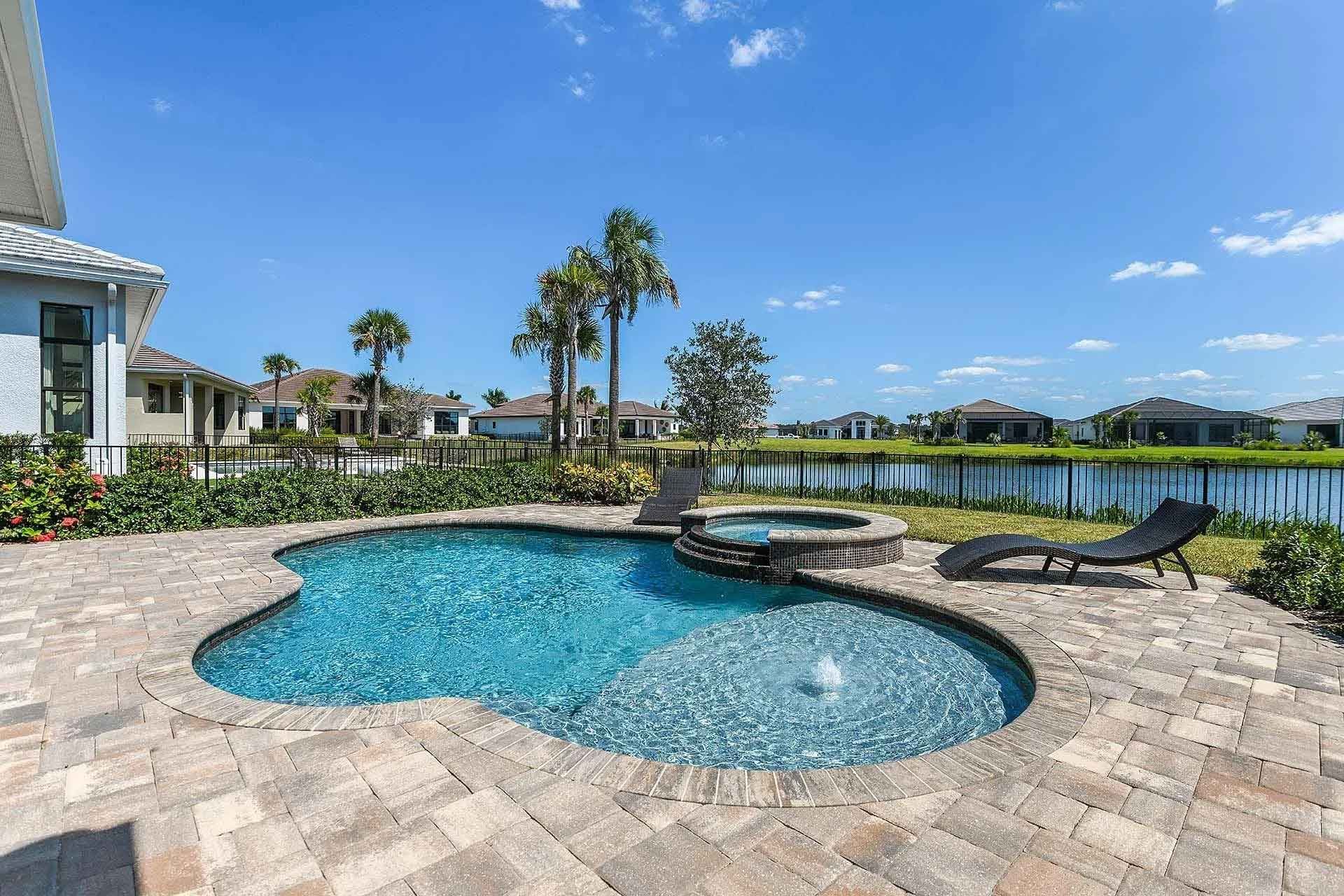 There is a large swimming pool in the backyard of a house.