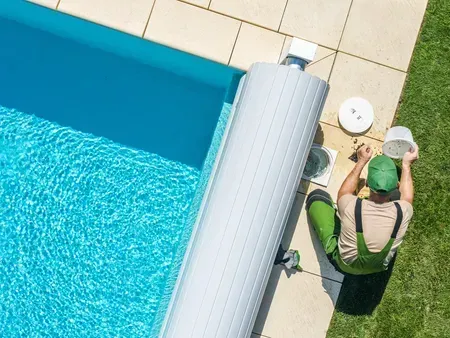 A man is sitting on the side of a swimming pool.