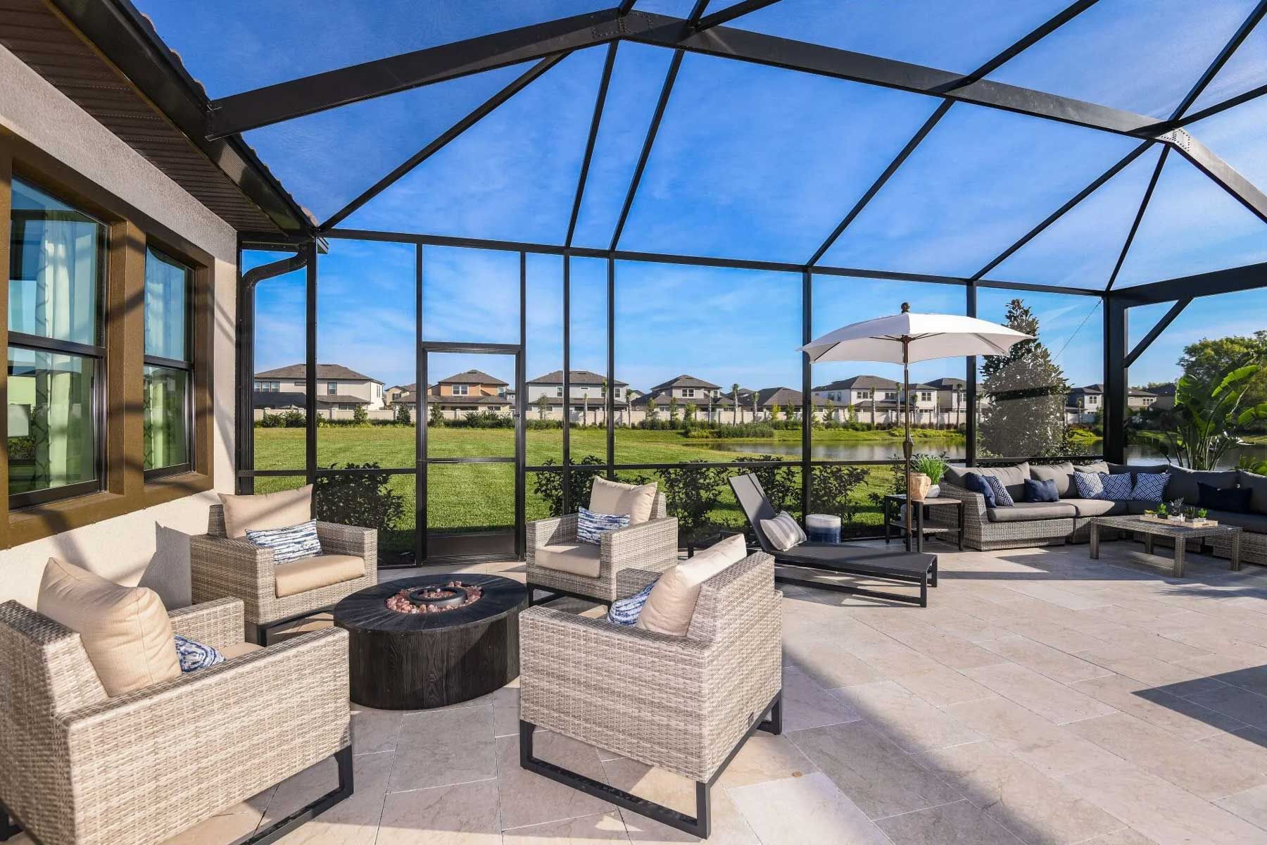 A screened in porch with wicker furniture and a fire pit.