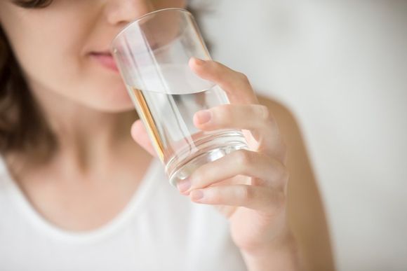 donna mentre beve un bicchiere d'acqua purificata