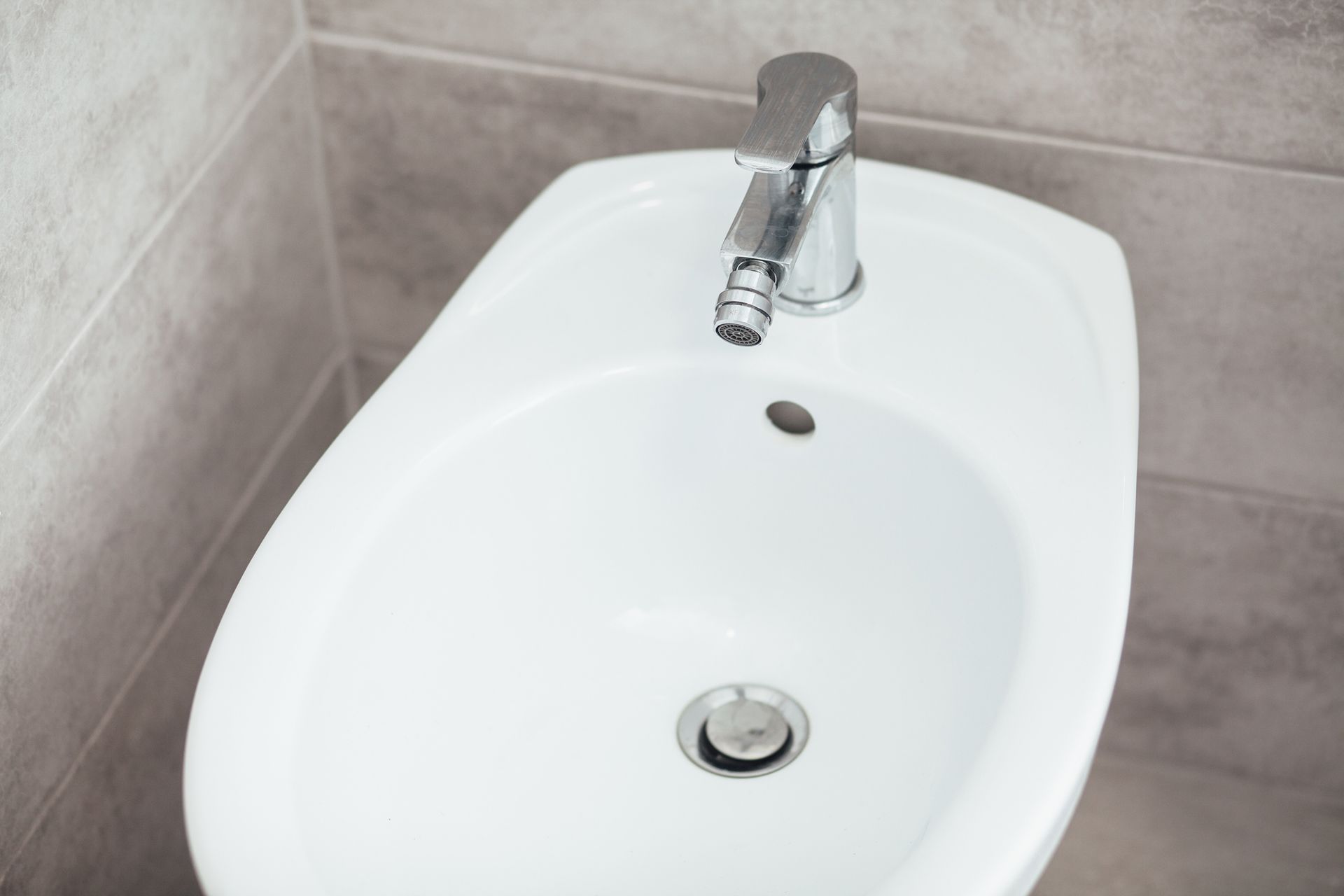 Un bidé blanco con grifo cromado en un baño.