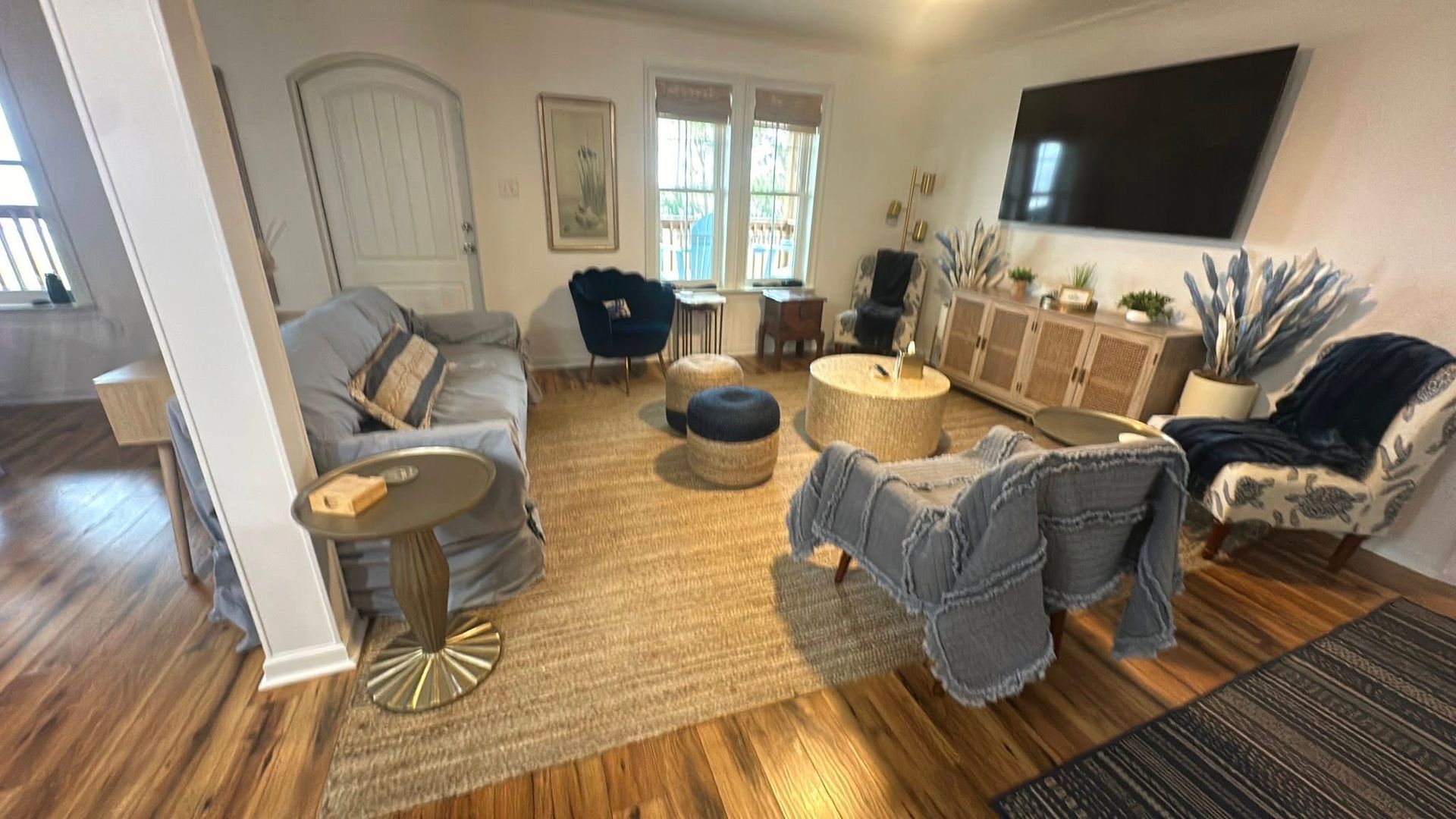 Living room with blue sofa, wooden floors, rug, and TV.