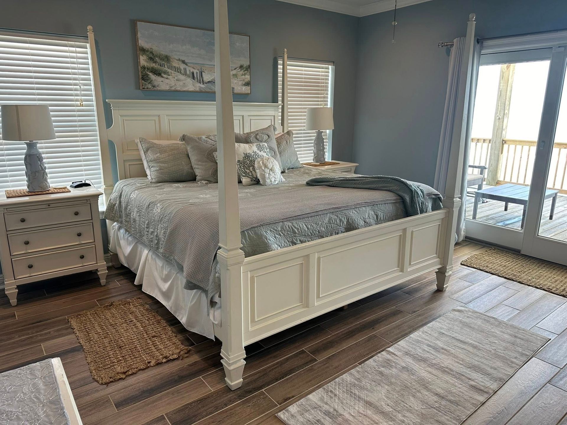 Bedroom with a white four-poster bed, nightstands, and sliding doors to a deck. Blue walls and wood floors.