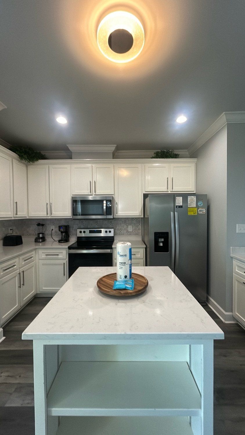Modern kitchen with white cabinets, stainless steel appliances, and a central island.