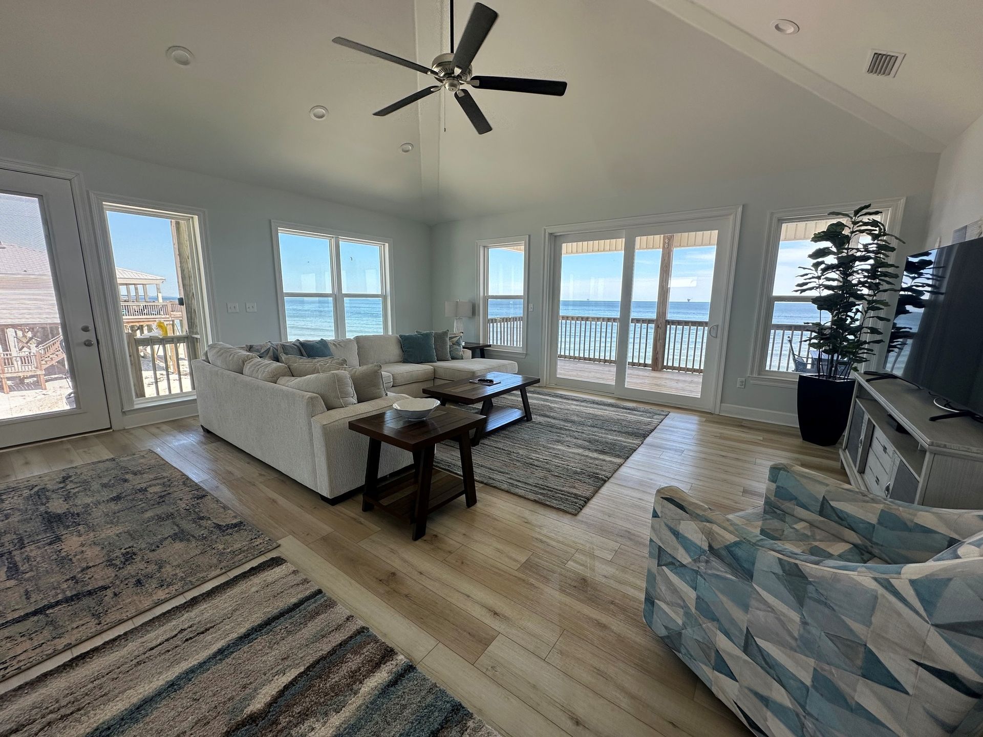 Living room with ocean view, white sectional, patterned rugs, and large windows.