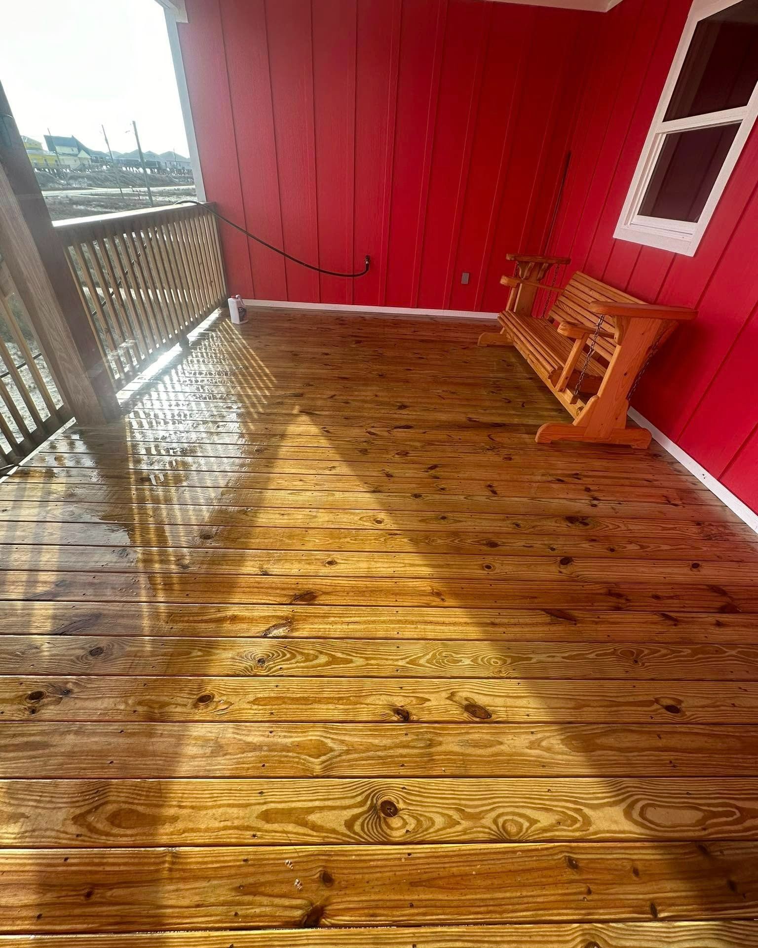 Wooden deck with a red wall and a wooden swing.