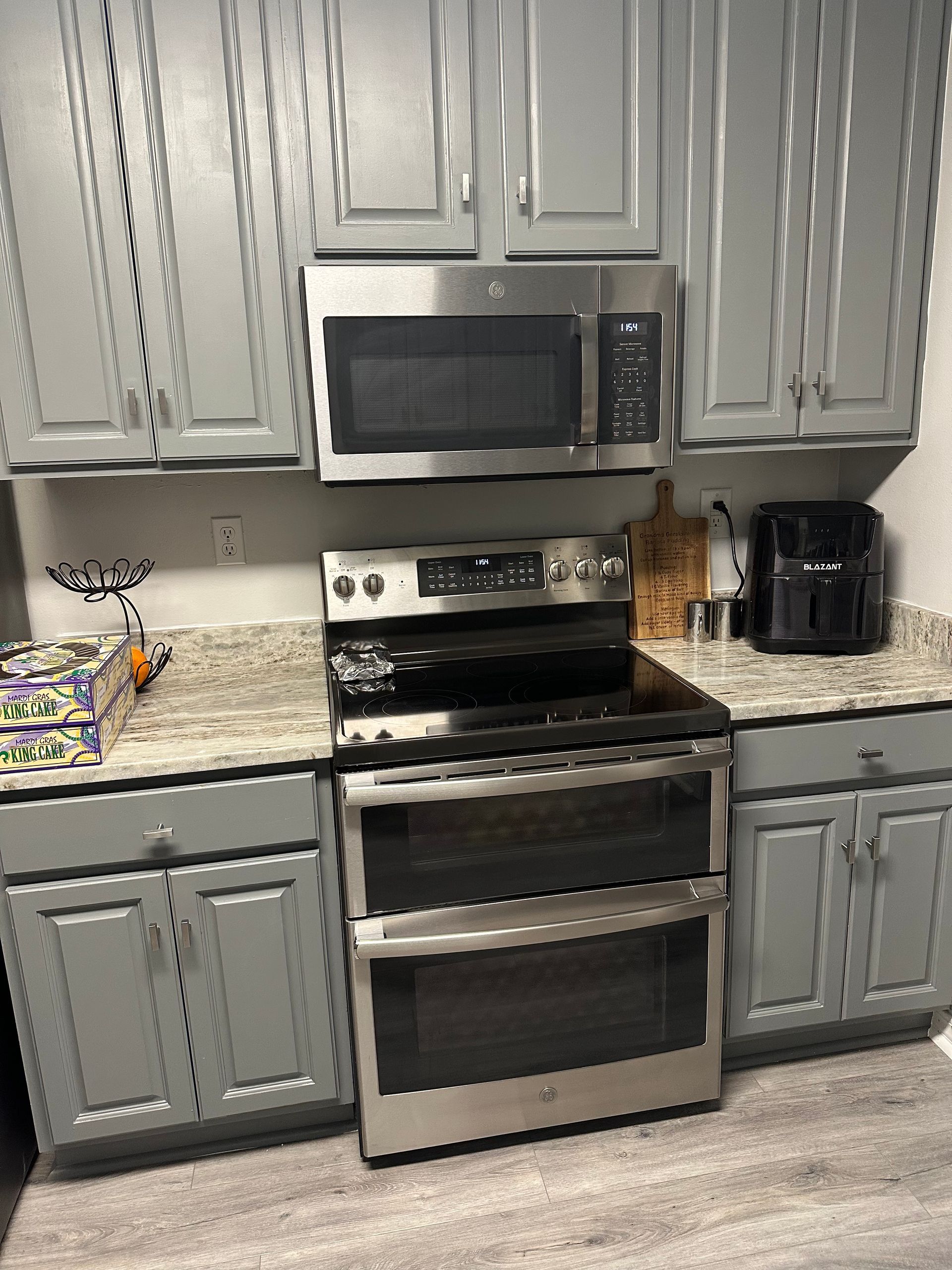 Kitchen featuring grey cabinets, granite countertops, and a stainless steel oven and microwave.