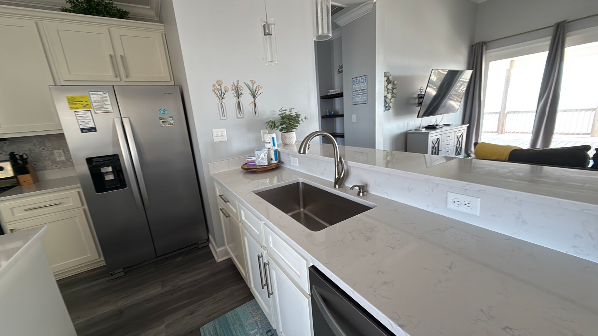 A modern kitchen with white cabinets, stainless steel appliances, and a quartz countertop with a sink.