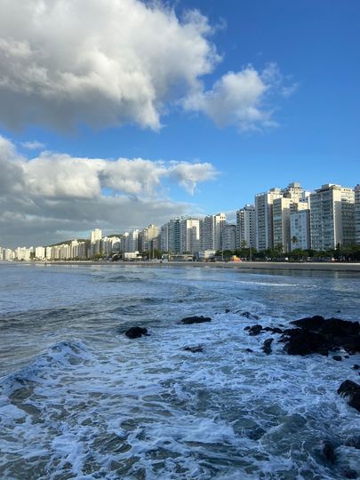Pessoa com uma bolsa puxando uma mala preta com rodinhas.