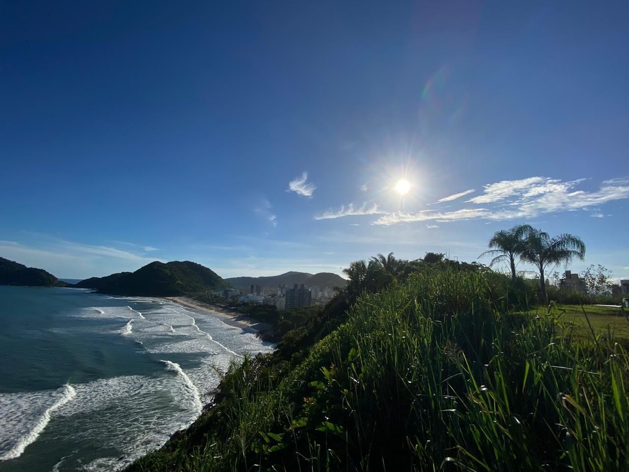 Pessoa com uma bolsa puxando uma mala preta com rodinhas.