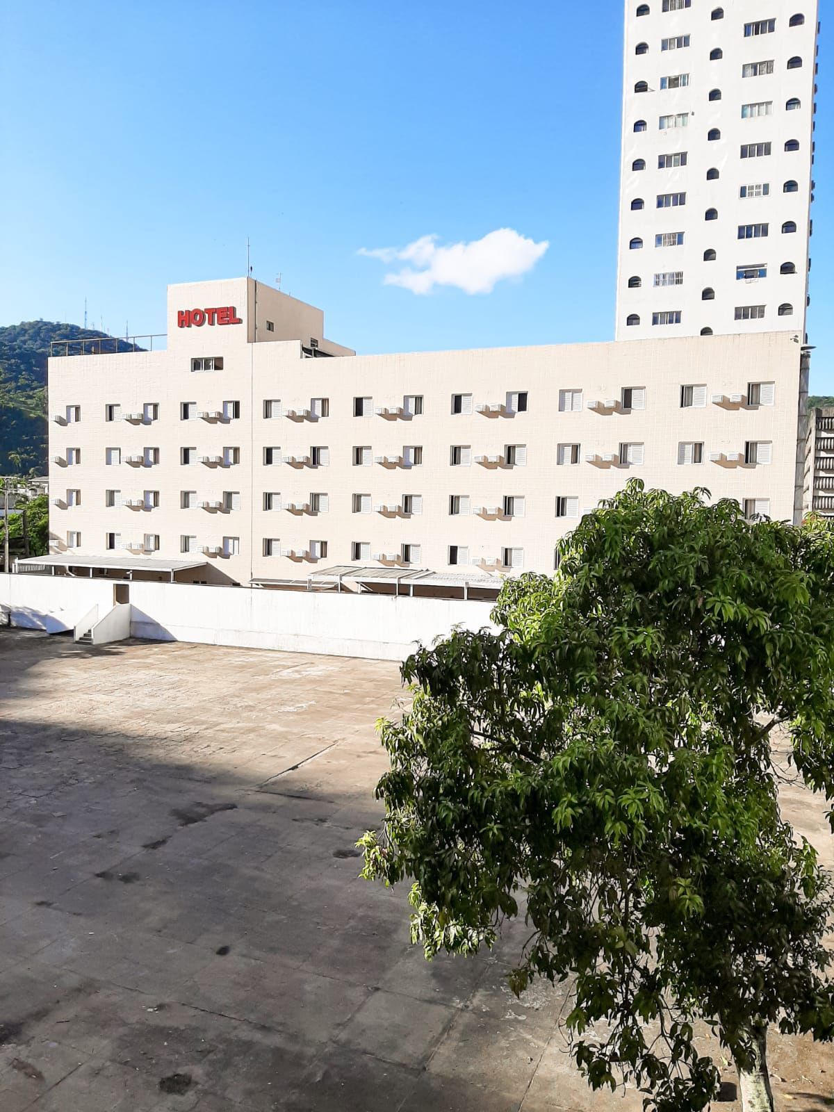 Prédio de hotel, de cor clara, com placa vermelha 