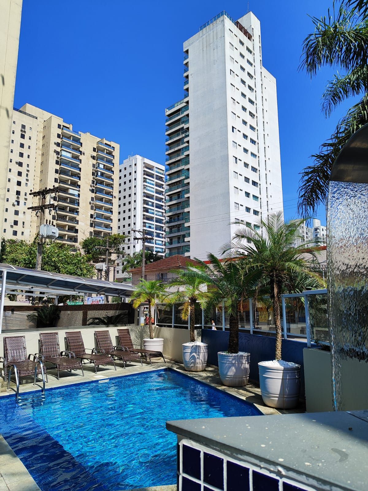 Piscina em frente a vários prédios altos em um dia ensolarado.