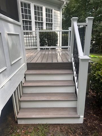 Wooden deck stairs leading to a deck with white railing and black balusters.