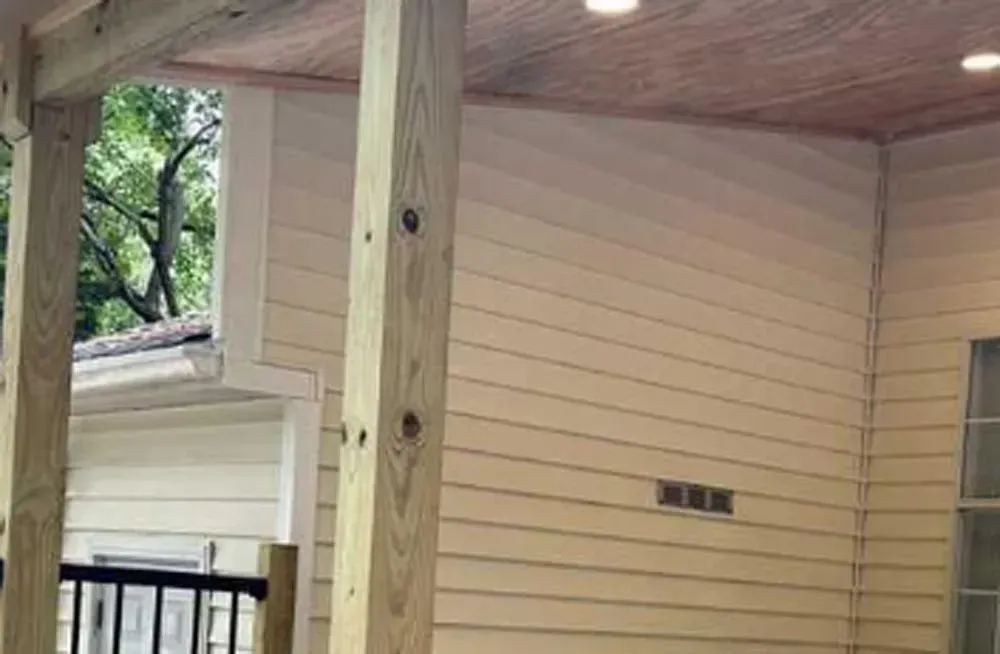 A porch with a wooden railing and a wooden ceiling.
