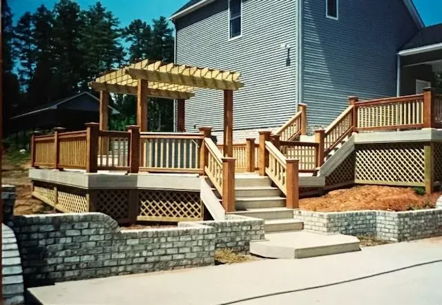 A deck with stairs and a pergola in front of a house