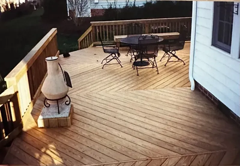 A wooden deck with a table and chairs and a fireplace