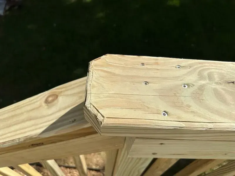 A close up of a wooden railing with screws in it.