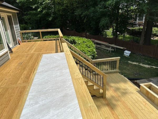 A wooden deck with stairs leading up to it and a house in the background.