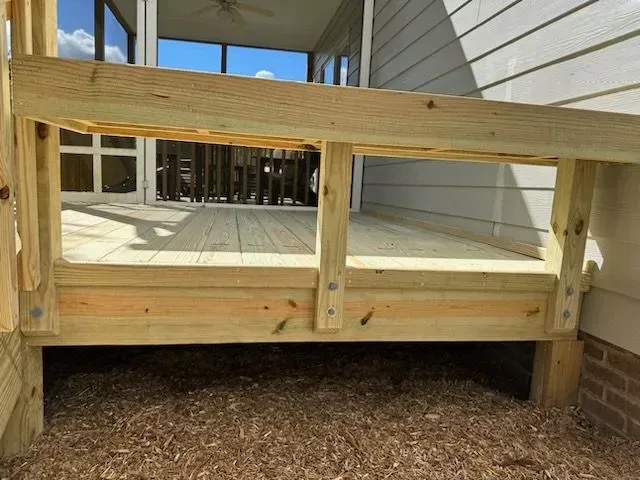 A wooden deck is being built in front of a house.