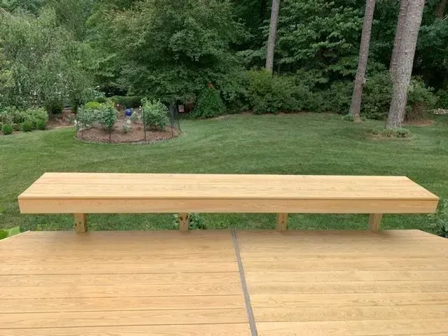 A wooden bench is sitting on top of a wooden deck.