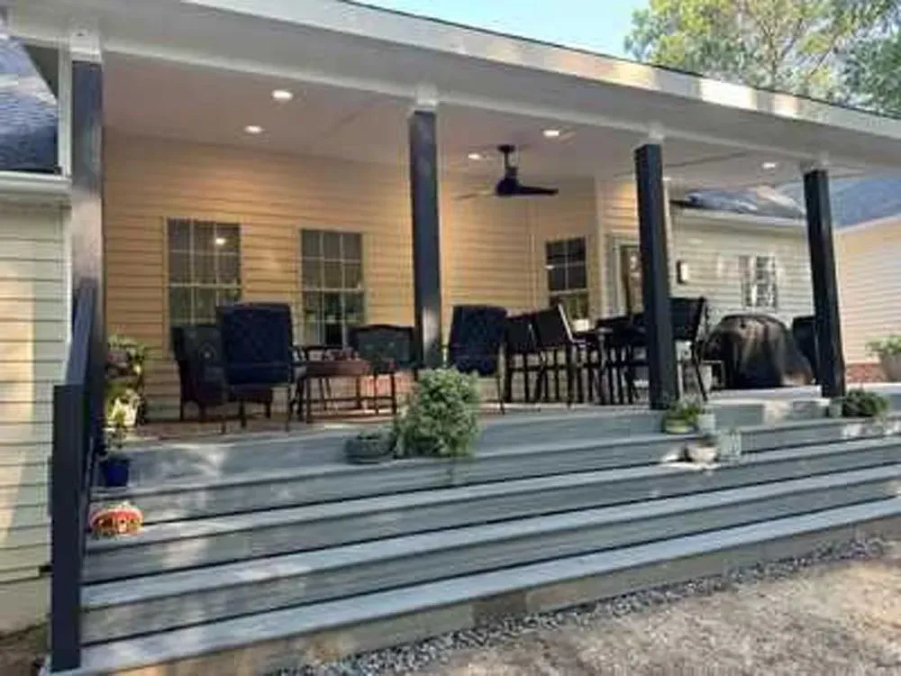 A large porch with a ceiling fan and a table and chairs on it.