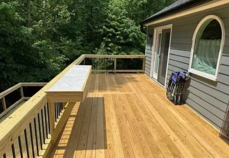 A wooden deck is sitting on the side of a house.