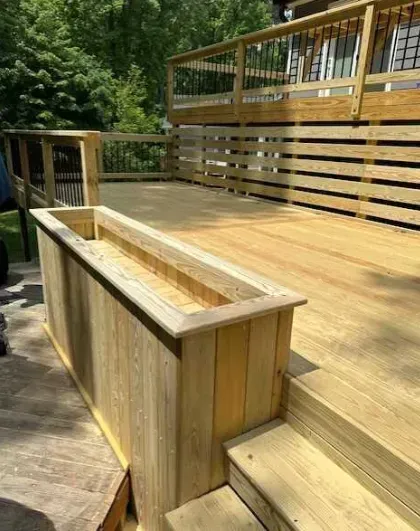 A wooden deck with stairs and a wooden planter.