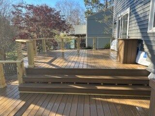 A wooden deck with stairs leading up to it is in front of a house.