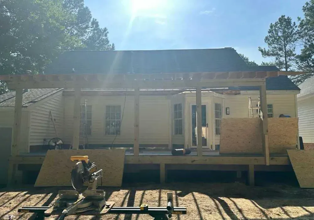 A wooden deck is being built in front of a house.