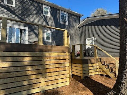 A wooden deck with stairs and a fence in front of a house.