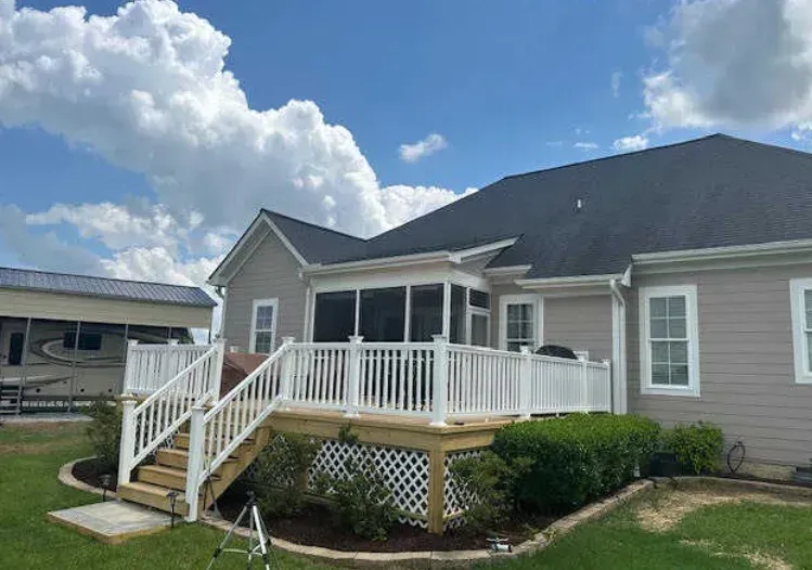 A house with a screened in porch and a white deck.