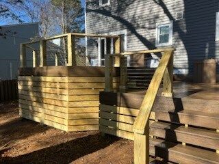 A wooden deck with stairs leading up to it in front of a house.