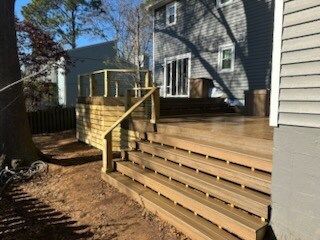 A wooden deck with stairs leading up to it next to a house.