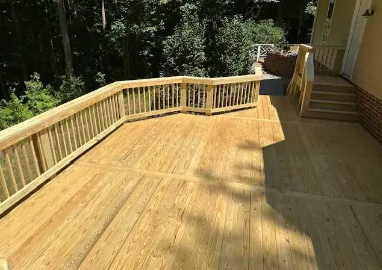 A large wooden deck with a railing and stairs leading up to it.