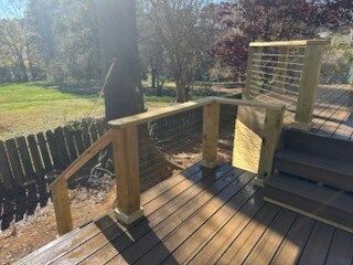 A wooden deck with stairs and a fence in the background.