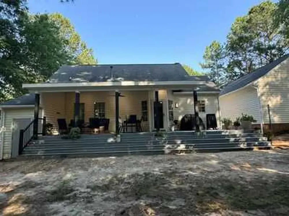 The back of a house with a large deck and stairs.