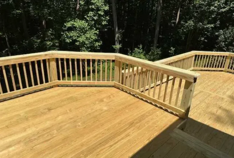 A wooden deck with a railing and trees in the background.
