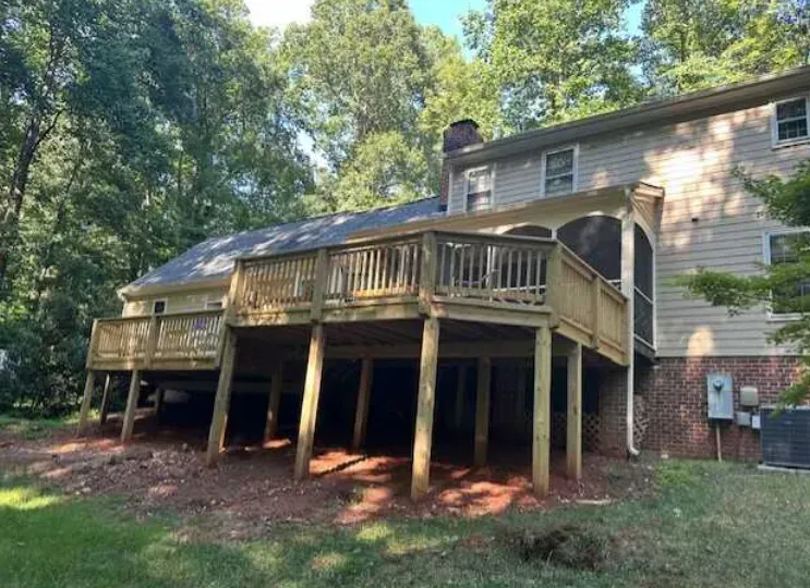 The back of a house with a large deck and screened in porch.